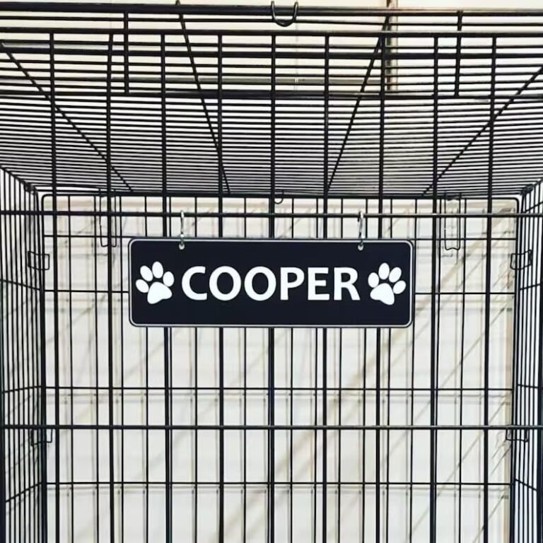 Dog crate with a sign that says "Cooper" and paw prints