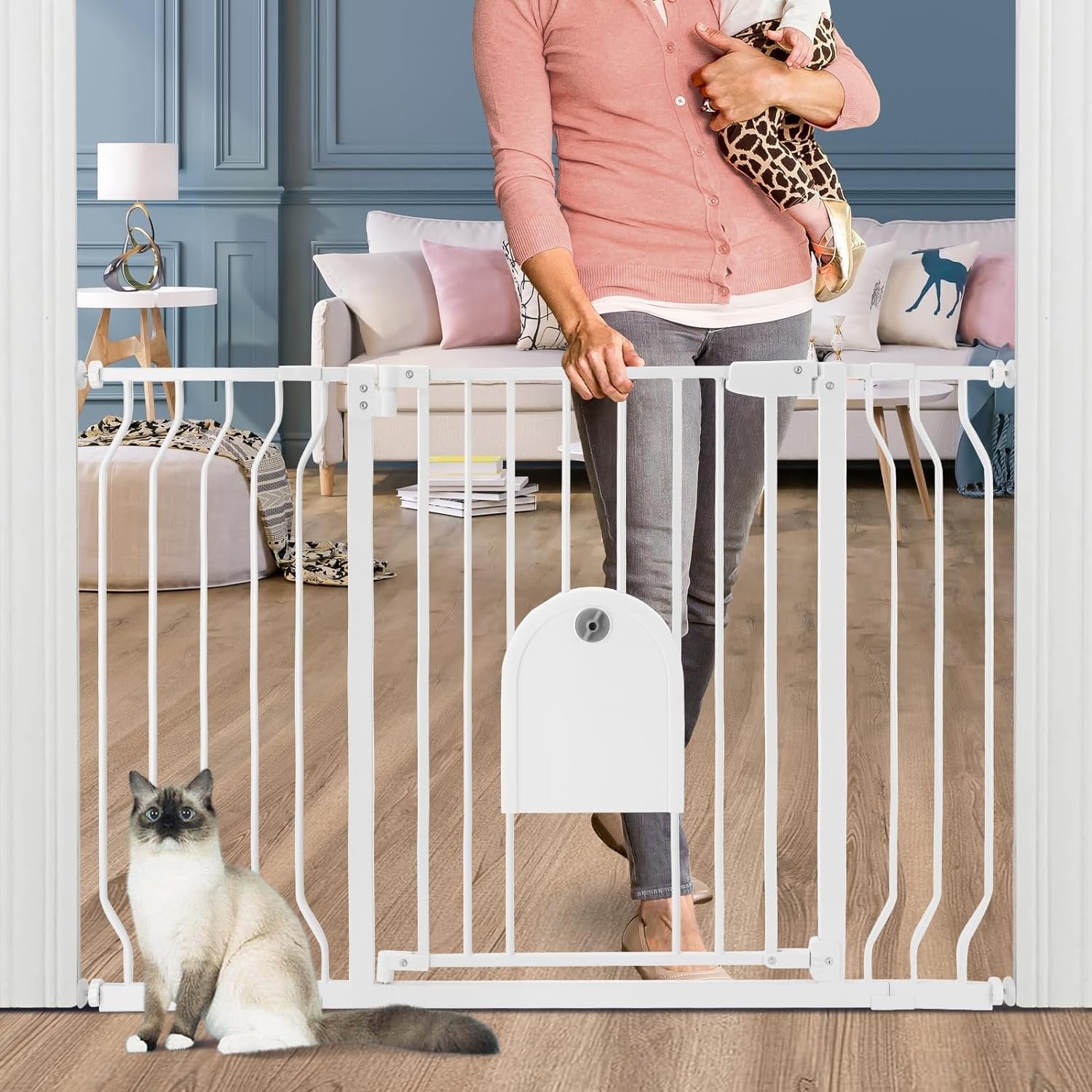 Woman holding baby, standing behind a white baby gate, cat in foreground