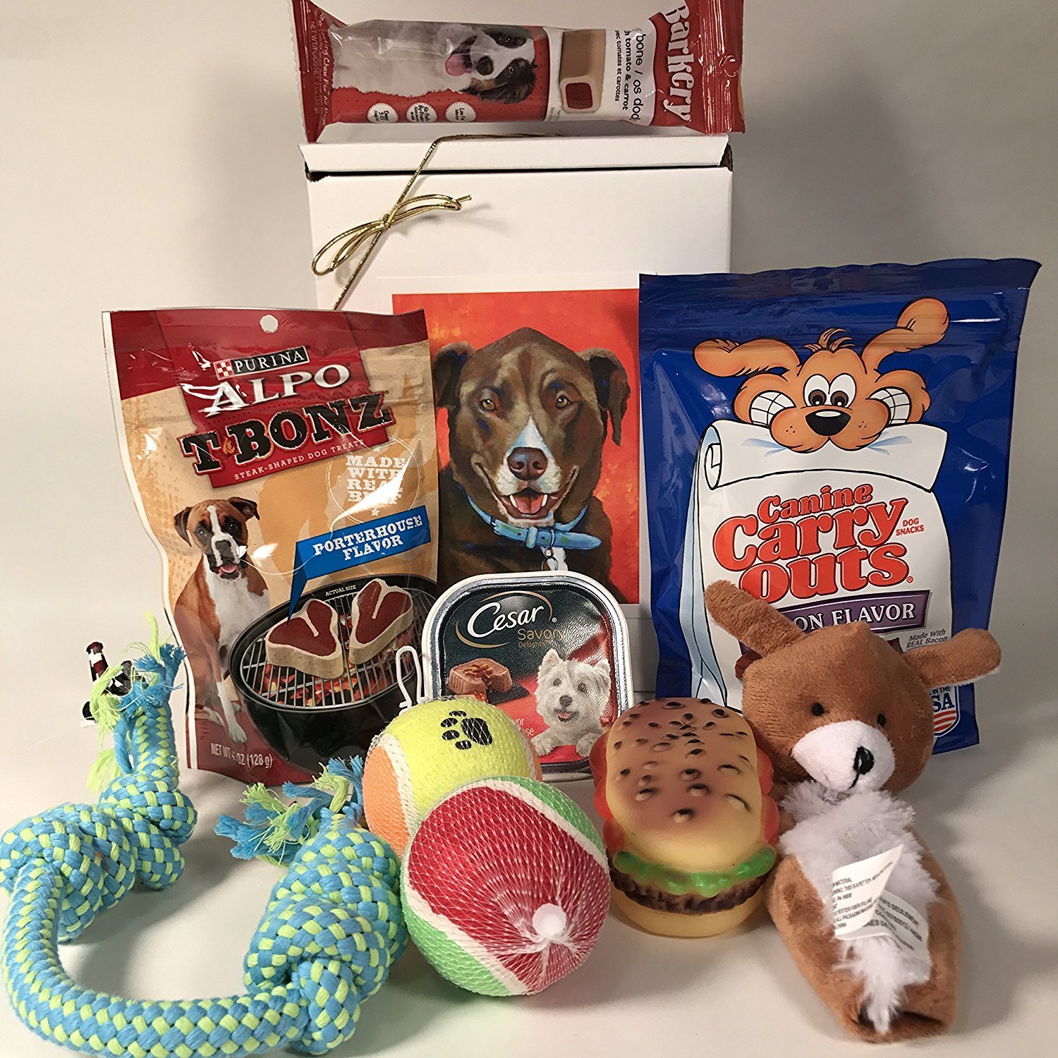 Dog treats, toys, and food items arranged for a gift basket